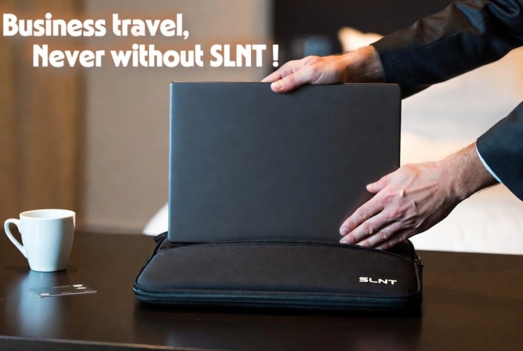 A business traveler securing a laptop inside a black SLNT Faraday sleeve in a hotel room to prevent data theft.